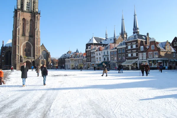 : daily and snowy main square of Delft in the Netherlands in the morning with people and blue sky