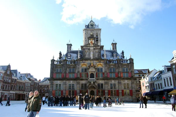 : daily and snowy main square of Delft in the Netherlands in the morning with people and blue sky