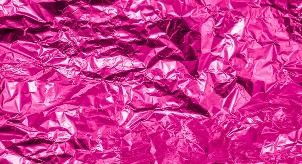 Pink crumpled aluminum foil texture background high contrasted
