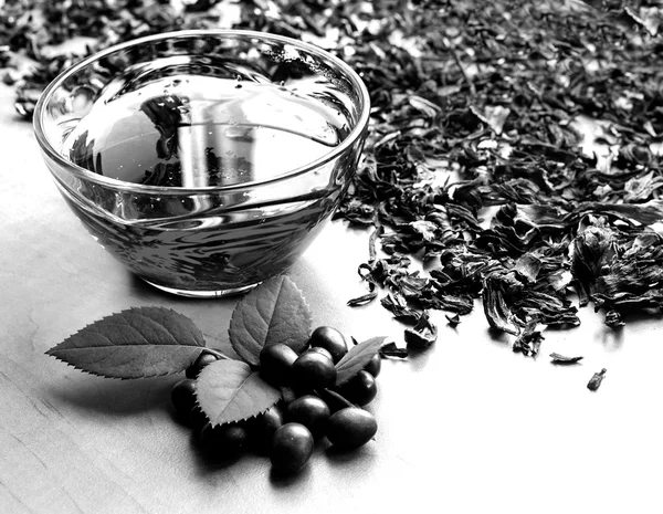 Still life cup of black tea with mint leaves on dried karkade tea background black and white