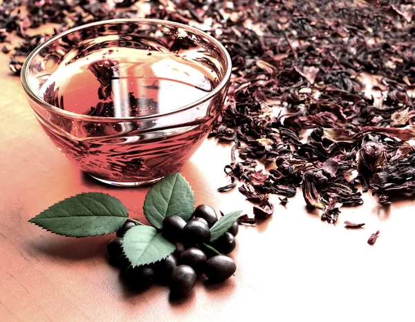 Still life cup of black tea with mint leaves on dried karkade tea background warm filtered