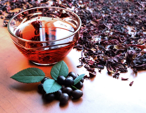 Still life cup of black tea with mint leaves on dried karkade tea background cold filtered