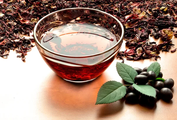Still life cup of black tea with mint leaves on dried karkade tea background warm filtered