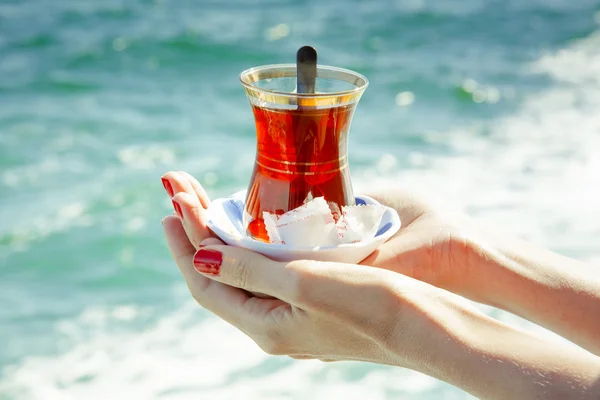A glass of Turkish tea in the hands on the background of the Bosphorus in Istanbul, Turkey.