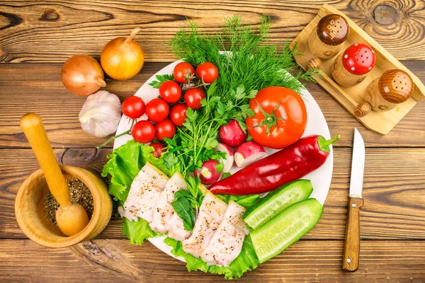 Plate with sliced fresh pork lard, fresh produce, vegetables on the wooden table.