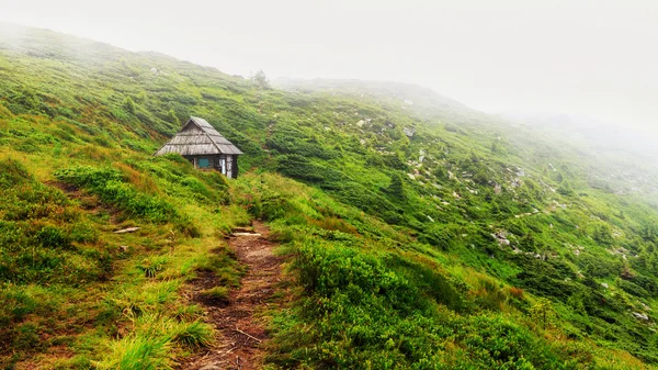 Mountain trail to the small wooden house on hill of ridge in Carpathians, Ukraine.