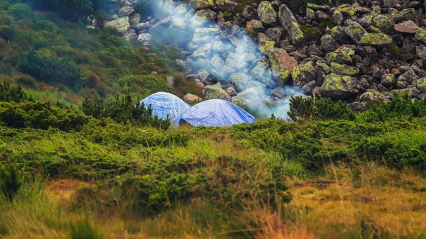 Camping tent and campfire smoke in Carpathian mountains, summertime journey.