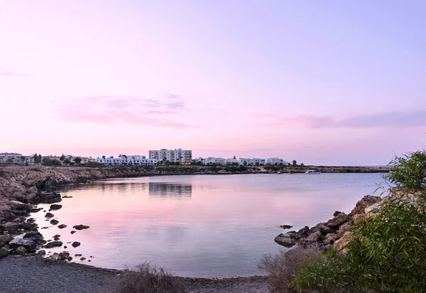 Photo of sea in protaras, cyprus island, with rocks and hotels at sunset.