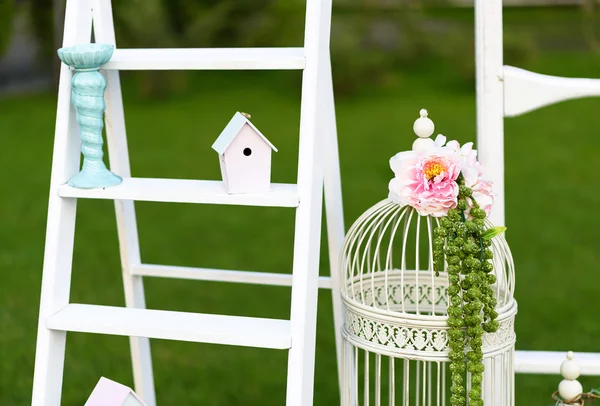 Vintage wedding decoration with white wooden wall, parrot and bird cage.