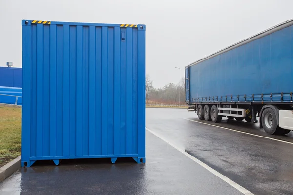 Blue transportation container and truck on parking