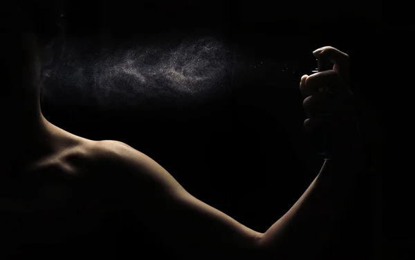 Woman\'s perfume in the hand on black background