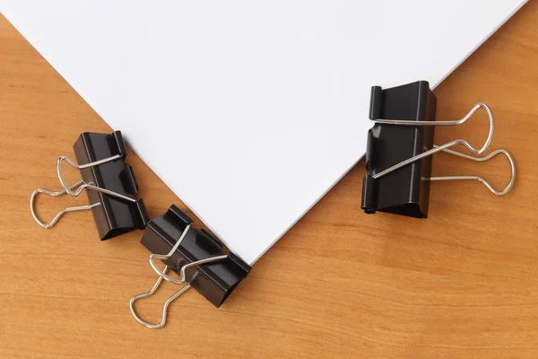 Two clips stapling papers on the table
