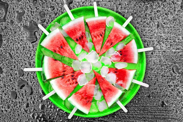 Slice of watermelon with ice cubes on a black background. Ice cream with the taste of watermelon