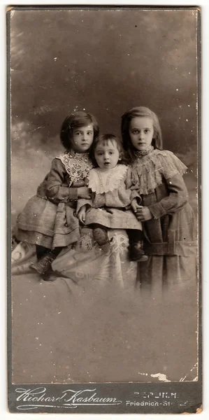A vintage cabinet card shows cute children (girls). Antique black & white photo.