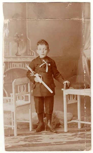 A vintage photo shows young boy - the first holy communion. Antique black & white photo with sepia tint.