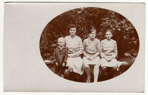 Vintage photo shows woman with daughters and son. Antique black & white photo is oval shape.