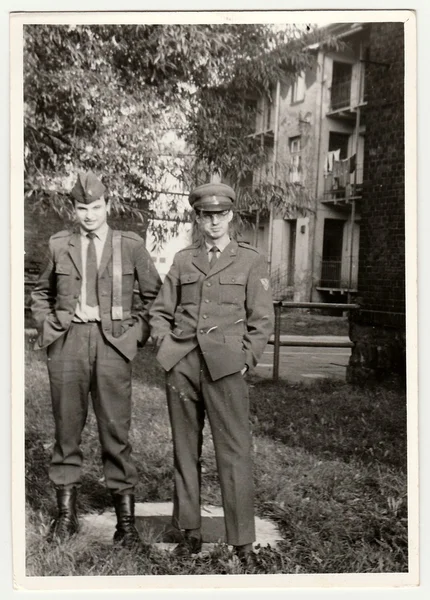 Vintage photo shows soldiers pose in front of barracks. Black & white antique photo.