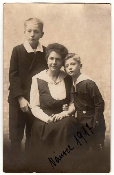 Vintage photo shows mother with children (boys). Black & white antique photography.
