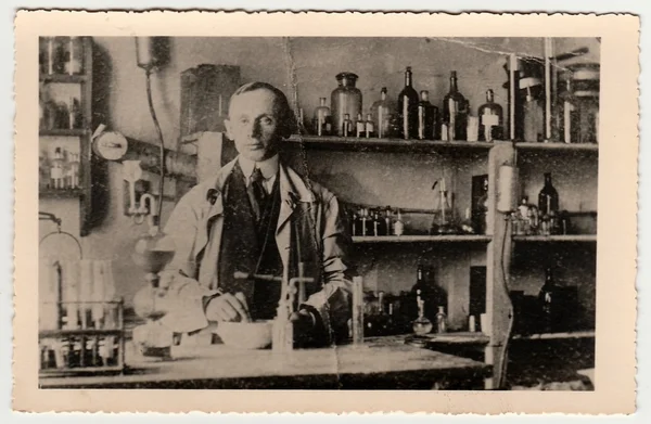 Vintage photo shows man in the chemistry laboratory. Black & white antique photography.