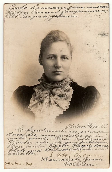 Vintage photo shows woman wears scarf. Used postcard contains handwriting. Rich stain and paper details. Can be used as background.