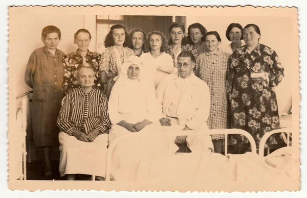 Vintage photo shows patients (women) and their doctor with  a hospital nun. Retro photography.
