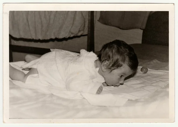 Retro photo shows cute baby crawls. Black & white vintage photography.