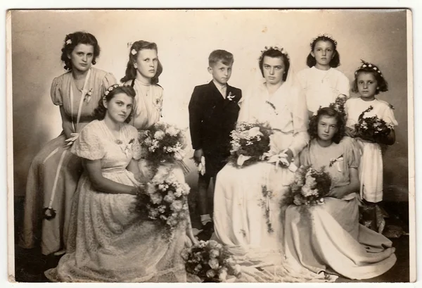 Retro photo shows young bride and bridesmaids (studio portrait). Black & white vintage photography.