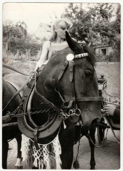 Retro photo shows young girl rides on the horse. Black & white vintage photography.