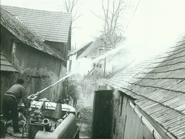 Retro photo shows fireman stands on the top of fire truck. Fireman demonstrates fire hose handling during a damage control exercise. Vintage black & white photography.