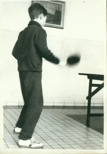 Retro photo shows young boy plays table tennis (ping-pong). Vintage black & white photography.