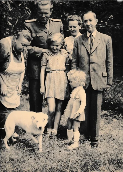Retro photo shows family and dog outside. Black & white vintage photography