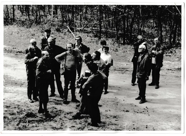 Retro photo shows tourists stand on the path. Black & white vintage photography