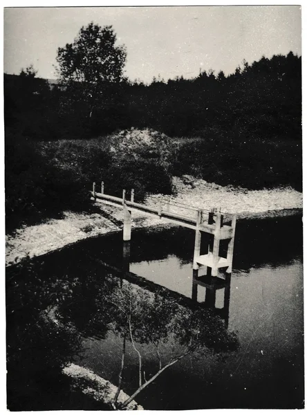 Retro photo shows sluice gate in the pond. Black & white vintage photography.