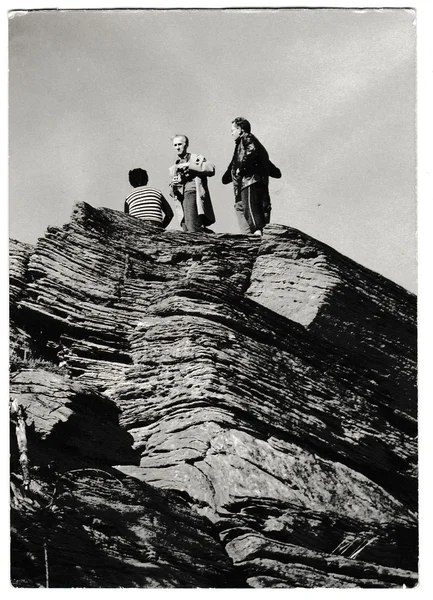 Retro photo shows tourists stand on top of the rock. People on holiday (vacation).  Black & white vintage photography