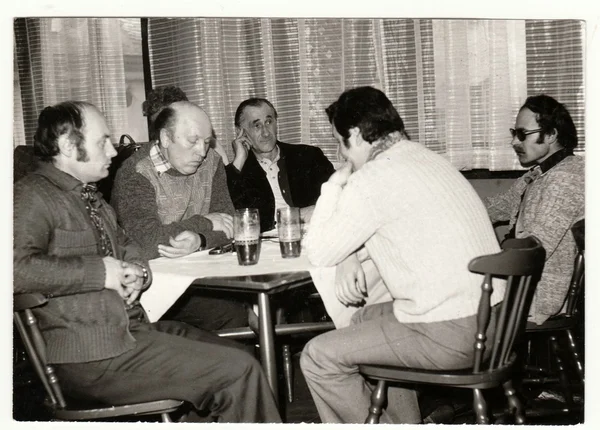 Retro photo shows men in the pub (inn). Vintage black & white photography.