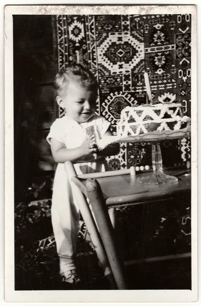 Vintage photo shows a boy to celebrate his first birthday. Birthday cake for boy. Retro black & white photography.