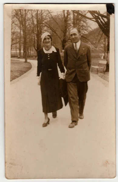 Vintage photo shows a couple goes for a walk in the city park. Retro black & white photography.