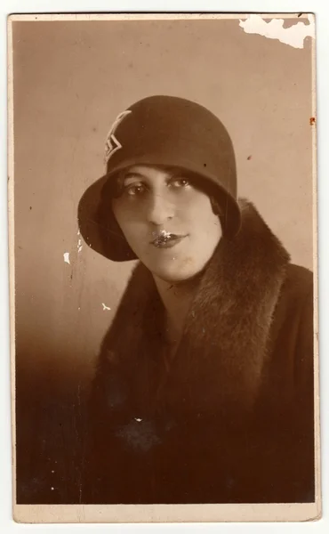 Vintage photo shows woman wears ladies hat (cloche hat) and fur scarf. Retro black & white photography.