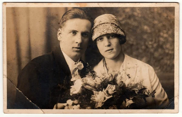 Vintage photo shows newlyweds. Wedding ceremony - bride and groom. Bride holds wedding flowers. Retro black & white photography.
