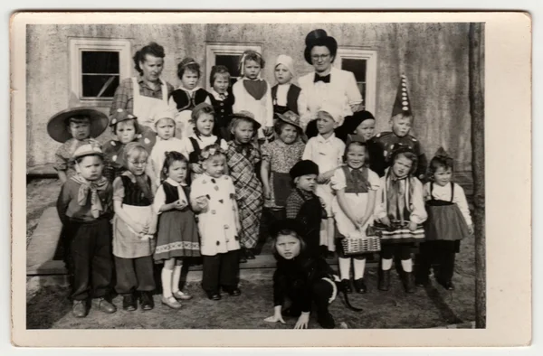 Vintage photo shows children/pupils wear funny costumes. Children pose after theatre performance. Black & white photography