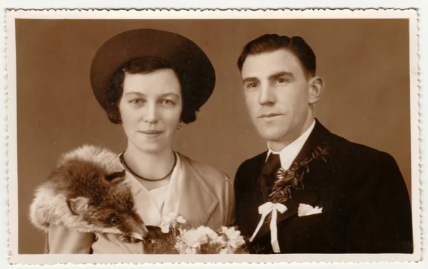 Vintage photo shows newlyweds. Wedding ceremony - bride and groom. Bride wears fox scarf. Retro black & white photography with sepia effect.