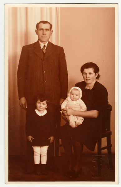 Vintage photo shows family in the photography studio. Retro black & white photography with sepia effect.