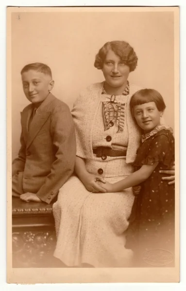 Vintage photo shows family - mother, son and daughter. Retro black & white studio photography with sepia effect.
