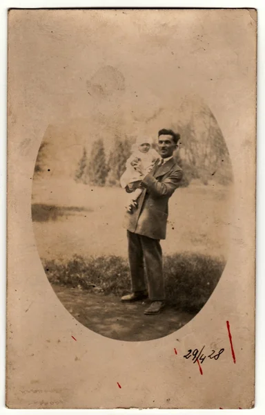 Vintage photo shows man cradles a small baby. Retro black & white photography.