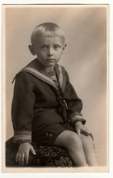 Vintage photo shows  a young boy wears sailor costume. Retro black & white photography.