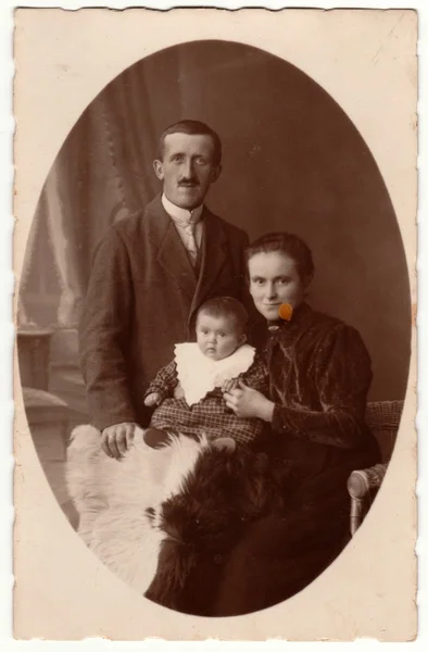 Vintage photo shows family - father, mother and baby boy. Retro black & white studio photography of a bourgeois family.