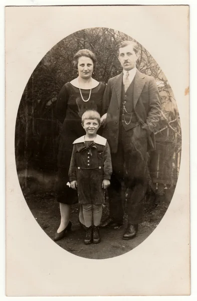 Vintage photo shows family - father, mother and a small boy. Retro black & white photography of a family.