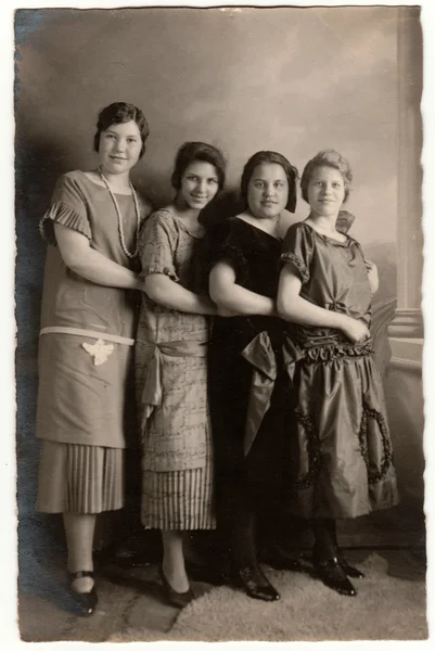 Vintage photo shows a group of girls poses in the photography studio. Retro black & white photography with sepia effect.