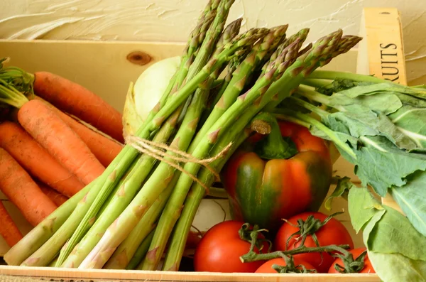 Peppers, asparagus, carrots and tomatoes in wooden box