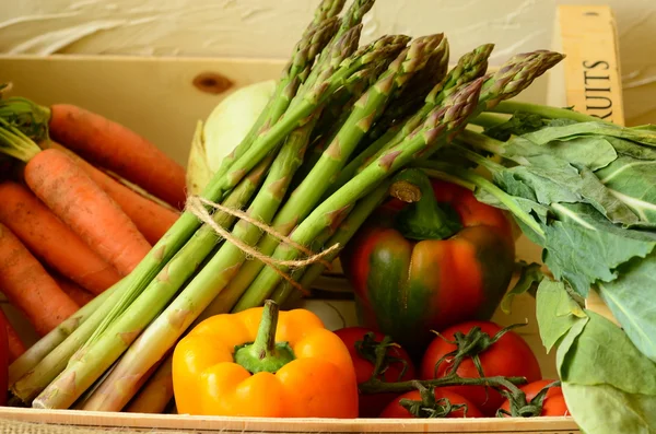 Peppers, asparagus, carrots and tomatoes in wooden box